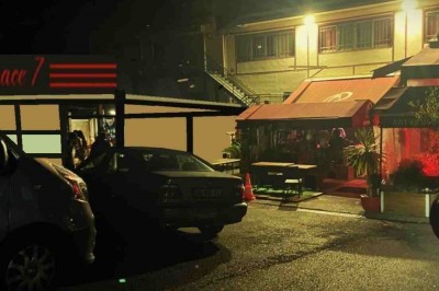 Salle sombre avec un public debout face à une scène éclairée où des musiciens jouent sous des projecteurs colorés.