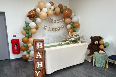 Salle de réception décorée avec des tables rondes dressées, nappes blanches, chandeliers et tapis rouge central.