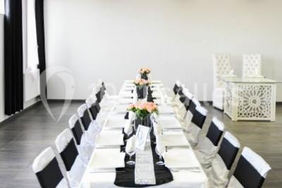 Salle de loisirs avec tables de billard, baby-foot, canapés noirs et murs rouges dans un espace lumineux.