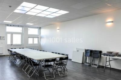 Salle de loisirs avec tables de billard, baby-foot, canapés noirs et murs rouges dans un espace lumineux.