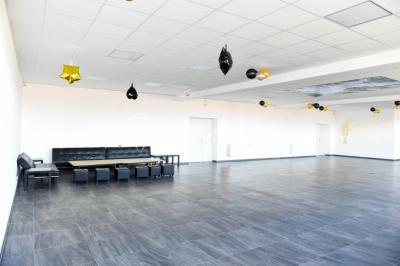 Salle de loisirs avec tables de billard, baby-foot, canapés noirs et murs rouges dans un espace lumineux.