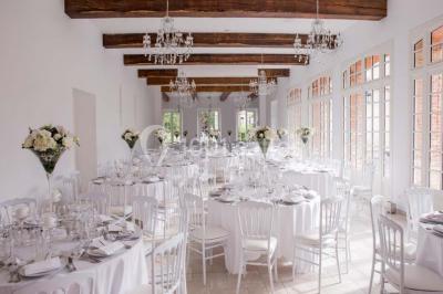 Salle de réception lumineuse avec des invités assis à des tables, discutant et partageant un repas.