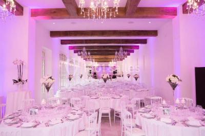 Salle de réception lumineuse avec des invités assis à des tables, discutant et partageant un repas.