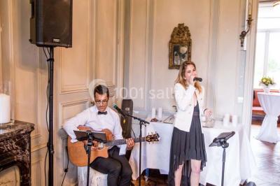 Salle de réception lumineuse avec des invités assis à des tables, discutant et partageant un repas.
