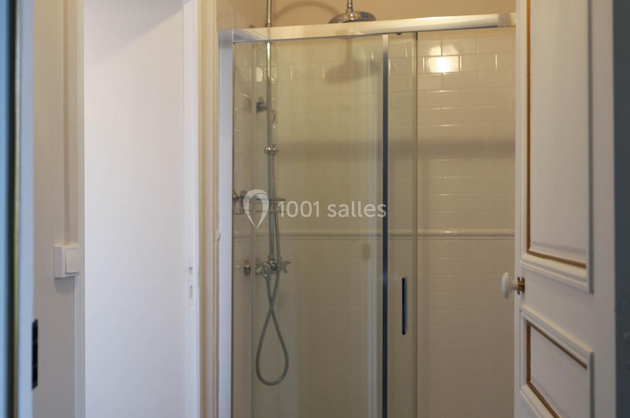 Douche moderne avec paroi vitrée dans une salle de bain aux murs clairs et sol en bois.