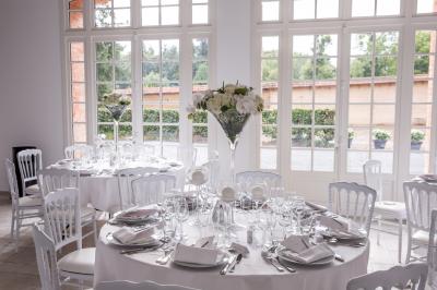 Salle de réception lumineuse avec des invités assis à des tables, discutant et partageant un repas.