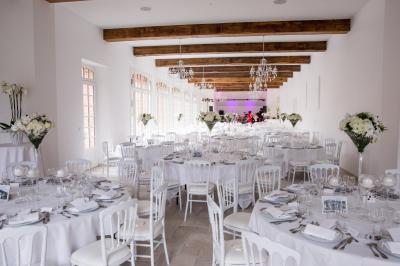 Salle de réception lumineuse avec des invités assis à des tables, discutant et partageant un repas.