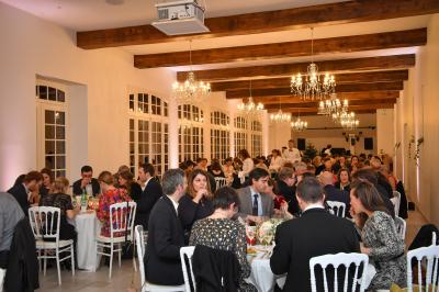 Salle de réception lumineuse avec des invités assis à des tables, discutant et partageant un repas.