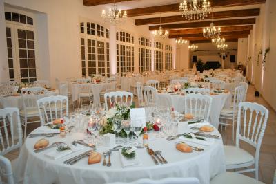 Salle de réception lumineuse avec des invités assis à des tables, discutant et partageant un repas.
