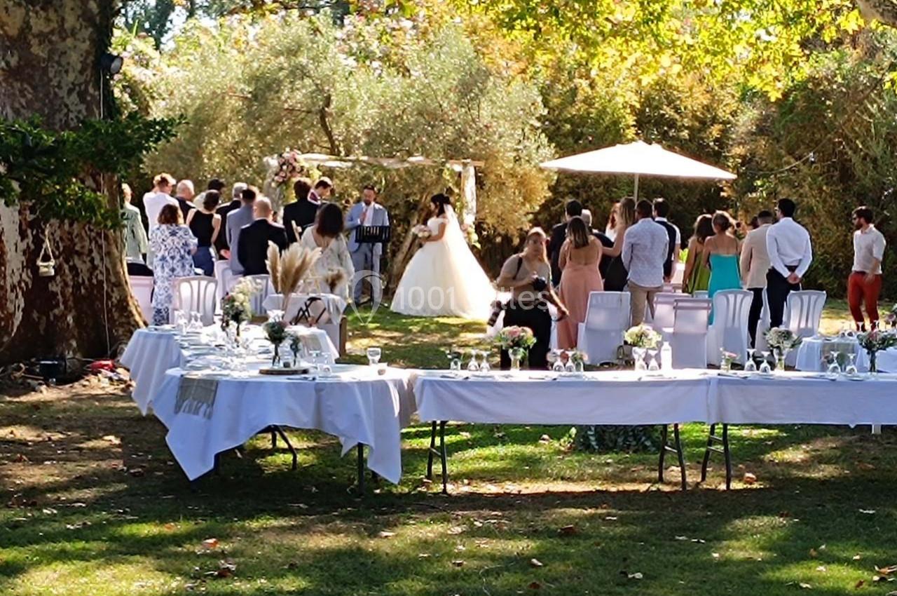 Location salle Fourques (Gard) - Domaine de la Tourette #5 Cérémonie de mariage en plein air avec des invités rassemblés sous les arbres, tables dressées au premier plan.
