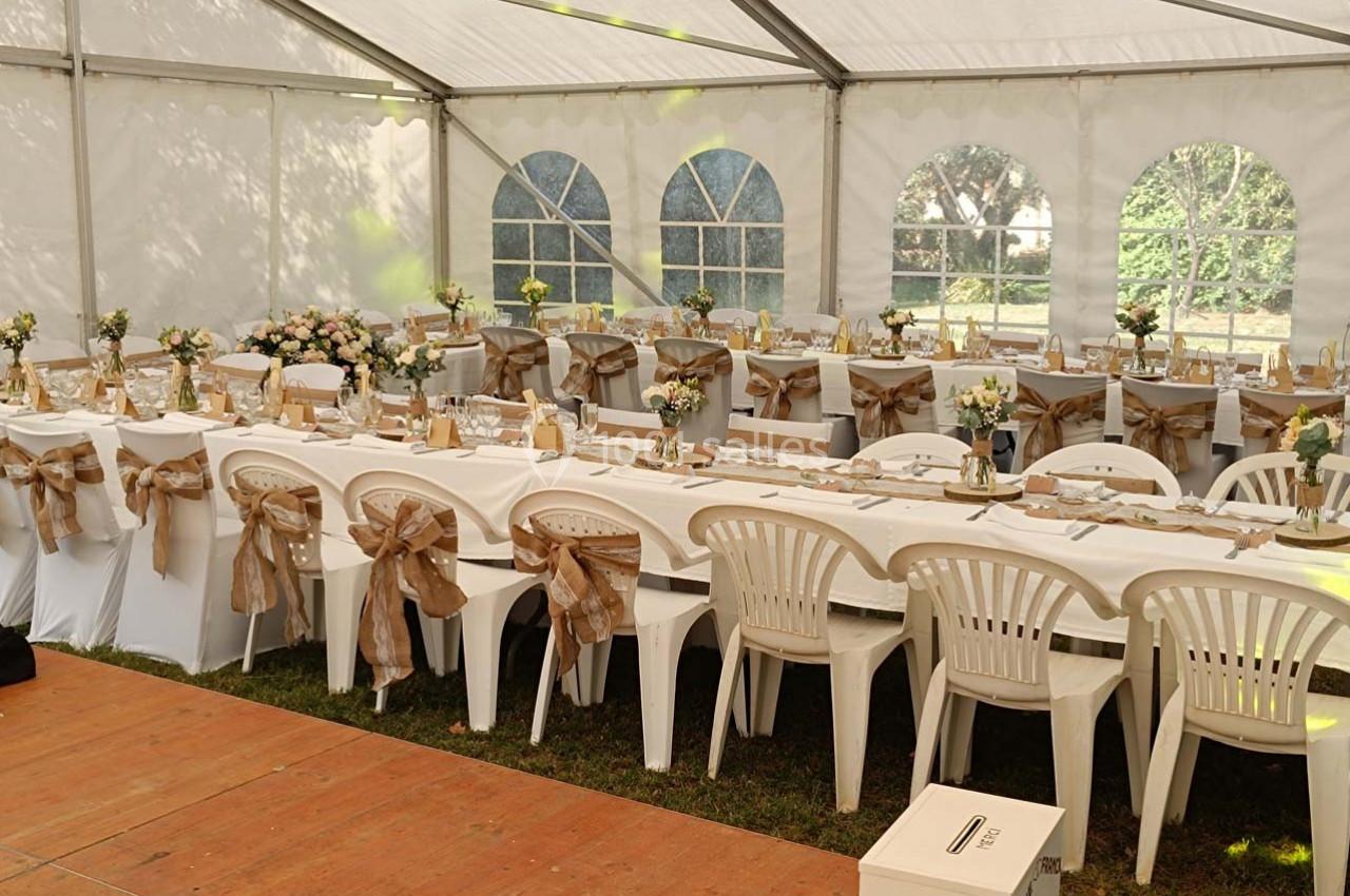 Location salle Fourques (Gard) - Domaine de la Tourette #4 Tables décorées avec nappes blanches, chaises ornées de rubans beiges, disposées sous une grande tente lumineuse.