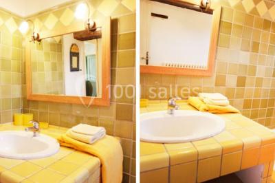 Miniature SALLE DE BAINS DU MANGUIN Lavabo avec plan de travail carrelé jaune, miroir encadré en bois et murs ornés de carreaux verts et jaunes.