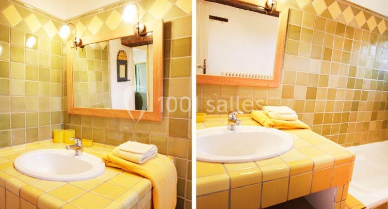 SALLE DE BAINS DU MANGUIN Lavabo avec plan de travail carrelé jaune, miroir encadré en bois et murs ornés de carreaux verts et jaunes.