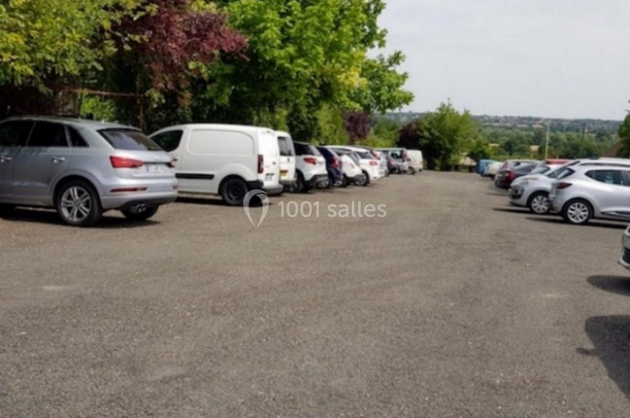 Parking extérieur avec plusieurs voitures stationnées, entouré d'arbres et offrant une vue dégagée sur l'horizon.