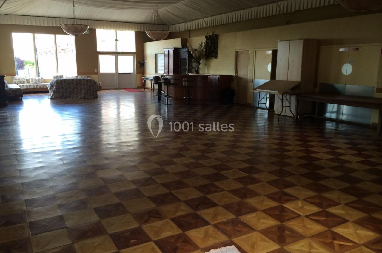 Salle spacieuse avec parquet en damier, mobilier minimaliste et grandes fenêtres laissant entrer la lumière naturelle.