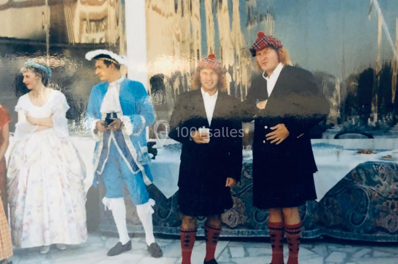 Personnes en costumes traditionnels et historiques rassemblées à l'extérieur près d'une table décorée.
