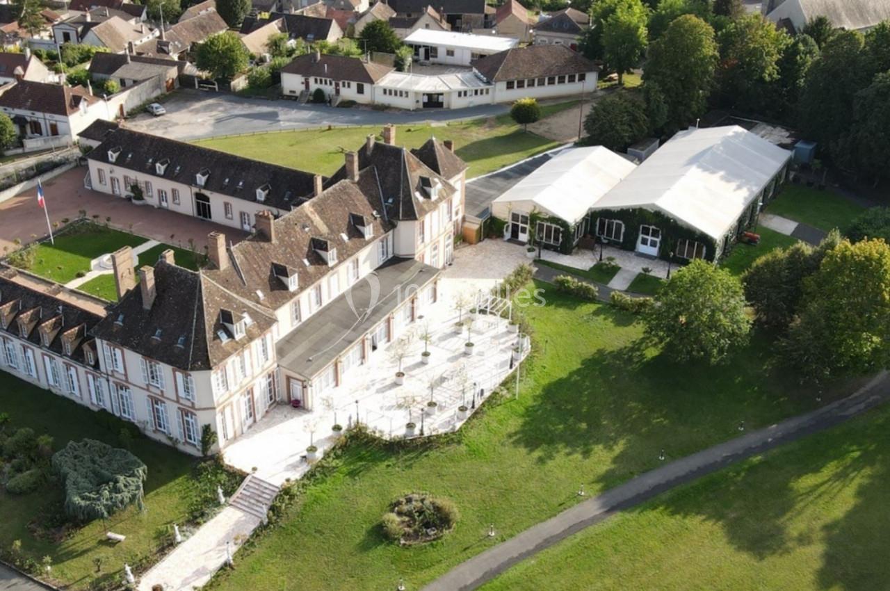 Vue aérienne d'un grand bâtiment historique entouré de jardins, avec des structures modernes et des espaces verts à…