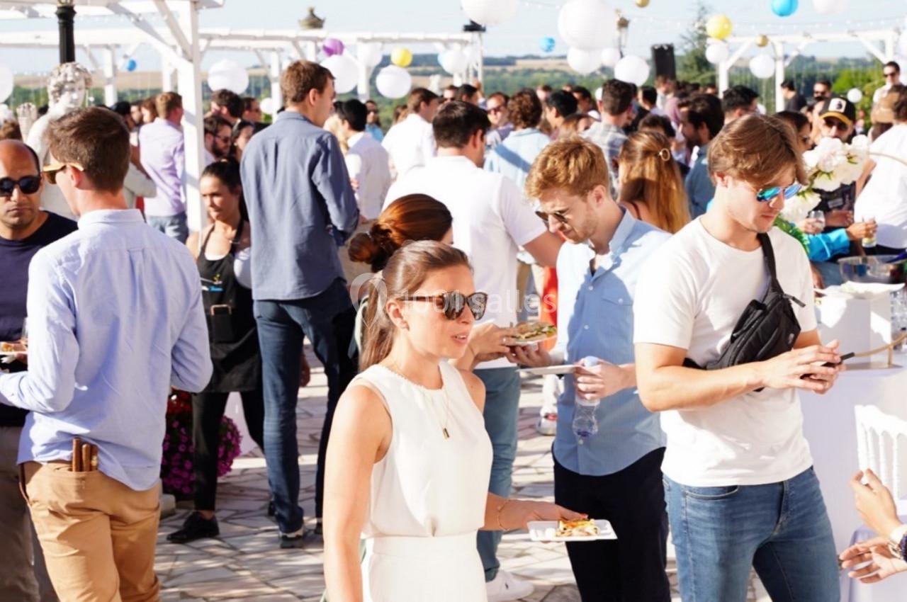Groupe de personnes échangeant et mangeant lors d'un événement en plein air sous un ciel ensoleillé.