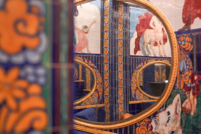 Miroirs ronds dorés reflétant des carreaux colorés ornés de motifs et illustrations dans un décor vibrant.