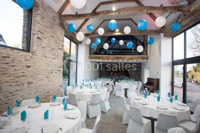 Table ronde décorée pour un repas, avec nappes blanches, couverts disposés, fleurs et éléments naturels en centre de table.