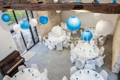 Table ronde décorée pour un repas, avec nappes blanches, couverts disposés, fleurs et éléments naturels en centre de table.