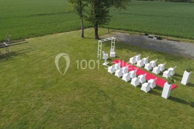 Table ronde décorée pour un repas, avec nappes blanches, couverts disposés, fleurs et éléments naturels en centre de table.