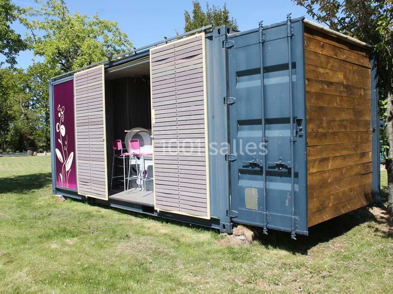 Un conteneur aménagé en espace habitable avec des volets coulissants, installé sur une pelouse.