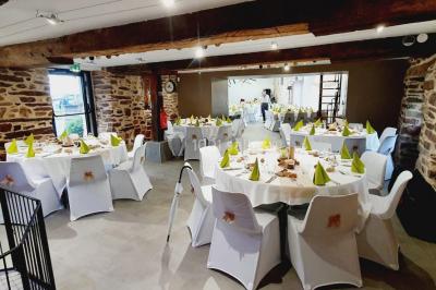 Table ronde décorée pour un repas, avec nappes blanches, couverts disposés, fleurs et éléments naturels en centre de table.