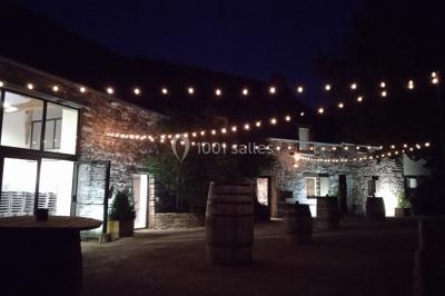 Table ronde décorée pour un repas, avec nappes blanches, couverts disposés, fleurs et éléments naturels en centre de table.