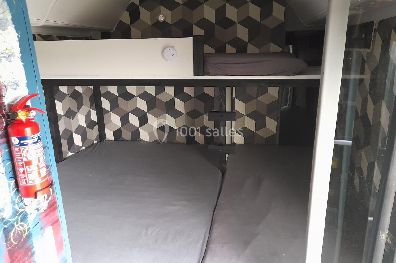 Lits superposés avec matelas gris dans un espace compact, décoré de motifs géométriques sur les murs.