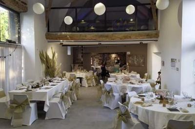 Table ronde décorée pour un repas, avec nappes blanches, couverts disposés, fleurs et éléments naturels en centre de table.
