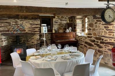 Table ronde décorée pour un repas, avec nappes blanches, couverts disposés, fleurs et éléments naturels en centre de table.