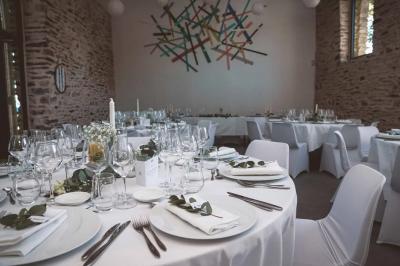 Table ronde décorée pour un repas, avec nappes blanches, couverts disposés, fleurs et éléments naturels en centre de table.