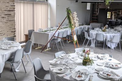 Table ronde décorée pour un repas, avec nappes blanches, couverts disposés, fleurs et éléments naturels en centre de table.