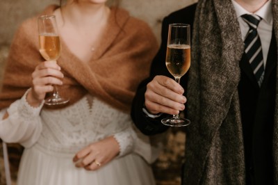 Robe de mariée en dentelle suspendue devant une fenêtre lumineuse avec vue sur un jardin verdoyant.