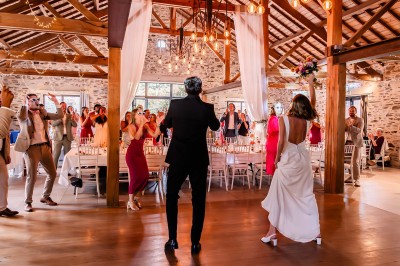 Robe de mariée en dentelle suspendue devant une fenêtre lumineuse avec vue sur un jardin verdoyant.