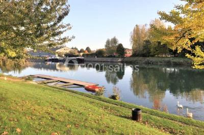 Terrasse extérieure avec tables dressées sous des parasols, entourée de verdure et visible à travers une fenêtre.
