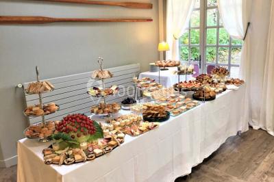 Terrasse extérieure avec tables dressées sous des parasols, entourée de verdure et visible à travers une fenêtre.