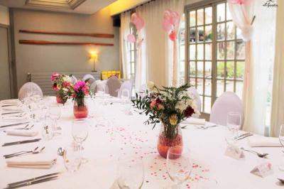 Terrasse extérieure avec tables dressées sous des parasols, entourée de verdure et visible à travers une fenêtre.