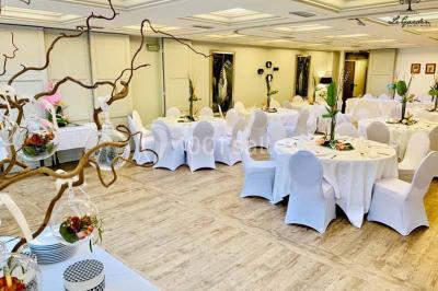 Terrasse extérieure avec tables dressées sous des parasols, entourée de verdure et visible à travers une fenêtre.