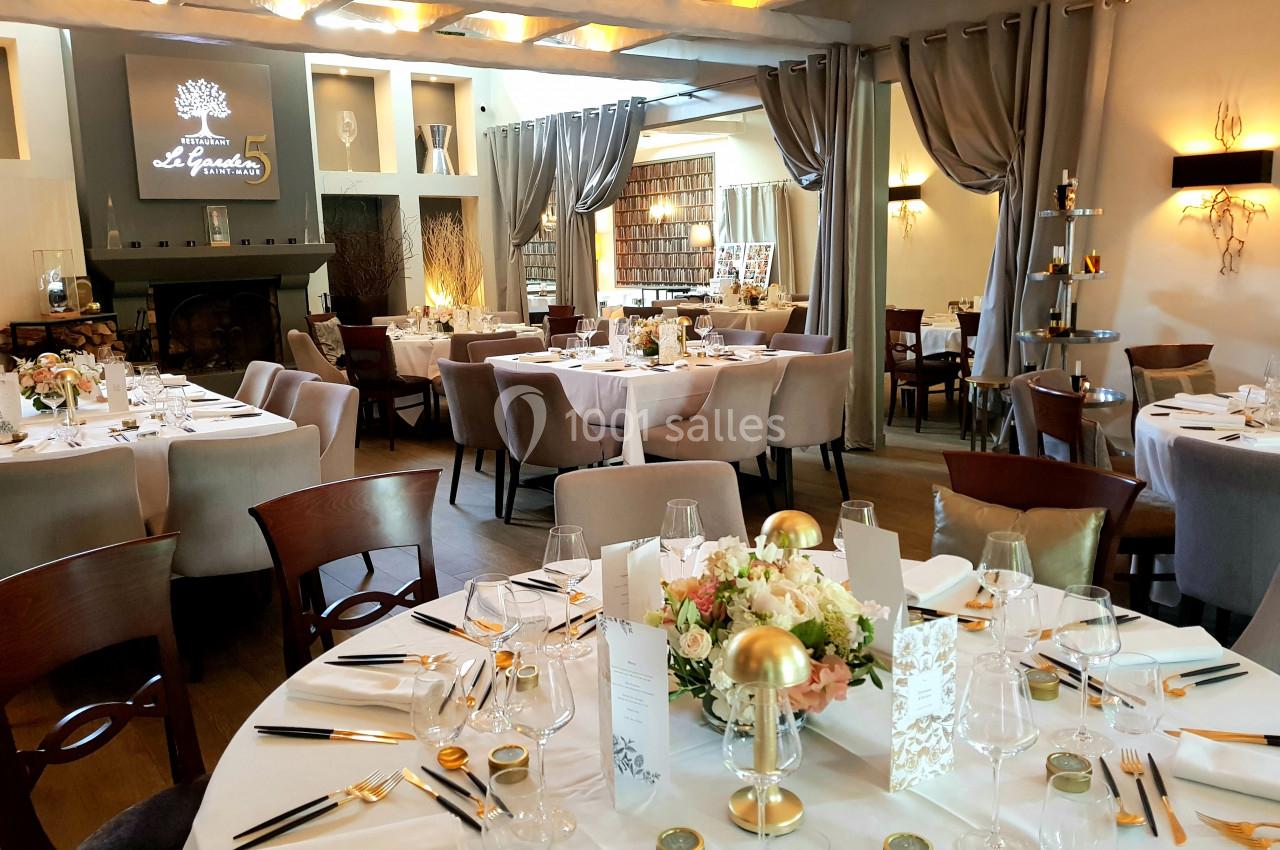 Salle de réception élégante avec tables rondes dressées, décor floral et ambiance chaleureuse.