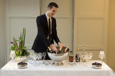 Terrasse extérieure avec tables dressées sous des parasols, entourée de verdure et visible à travers une fenêtre.