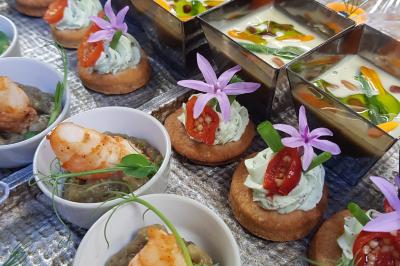 Terrasse extérieure avec tables dressées sous des parasols, entourée de verdure et visible à travers une fenêtre.