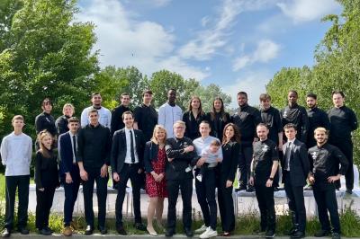 Terrasse extérieure avec tables dressées sous des parasols, entourée de verdure et visible à travers une fenêtre.
