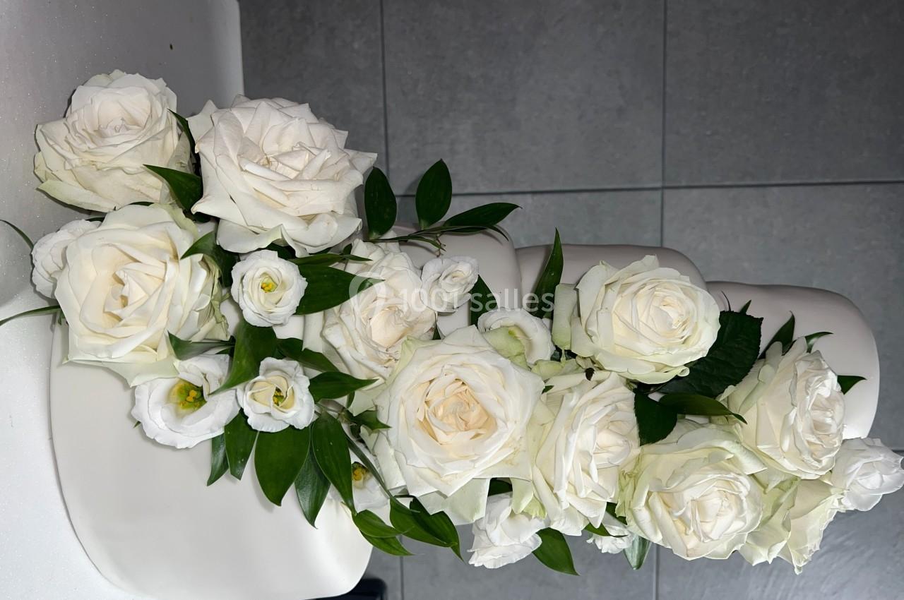 Décoration florale composée de roses blanches et de feuillage disposée sur un gâteau à plusieurs étages.