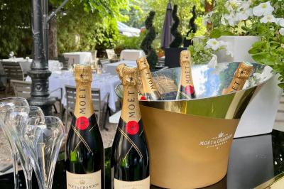 Terrasse extérieure avec tables dressées sous des parasols, entourée de verdure et visible à travers une fenêtre.