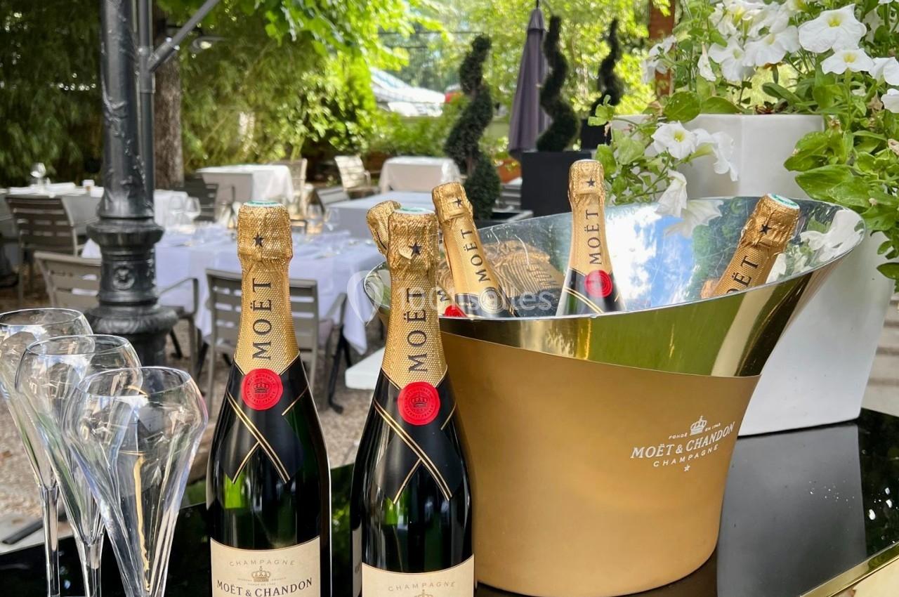 Bouteilles de champagne Moët & Chandon avec flûtes en verre sur une table extérieure, entourée de verdure.