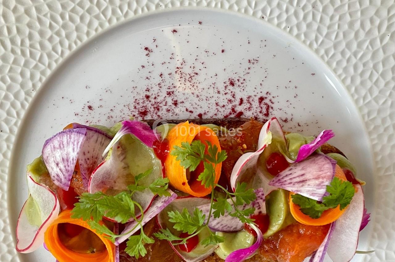 Assiette garnie de légumes colorés finement coupés, disposés sur une base avec des herbes fraîches et une touche de sauce.