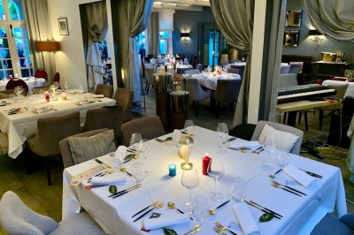Terrasse extérieure avec tables dressées sous des parasols, entourée de verdure et visible à travers une fenêtre.