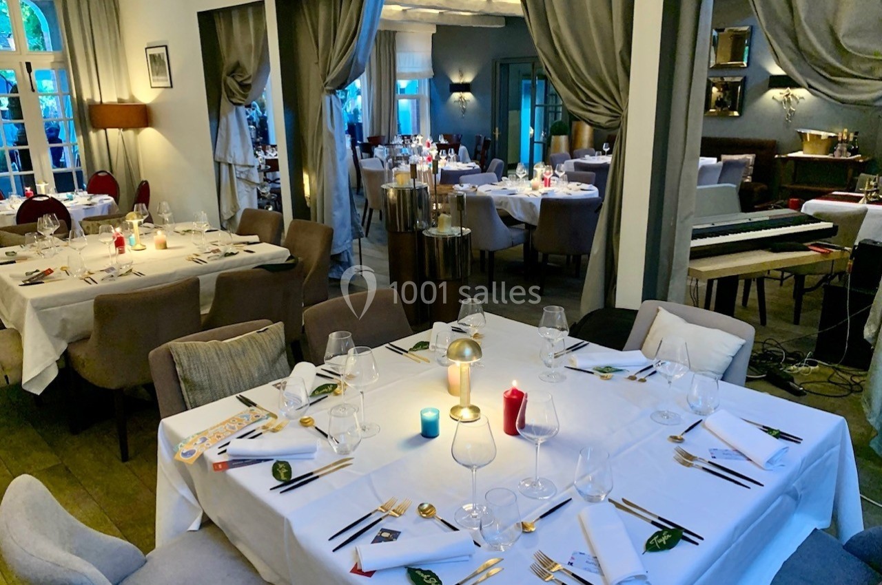 Salle de restaurant élégante avec tables dressées, nappes blanches, bougies colorées et ambiance chaleureuse.